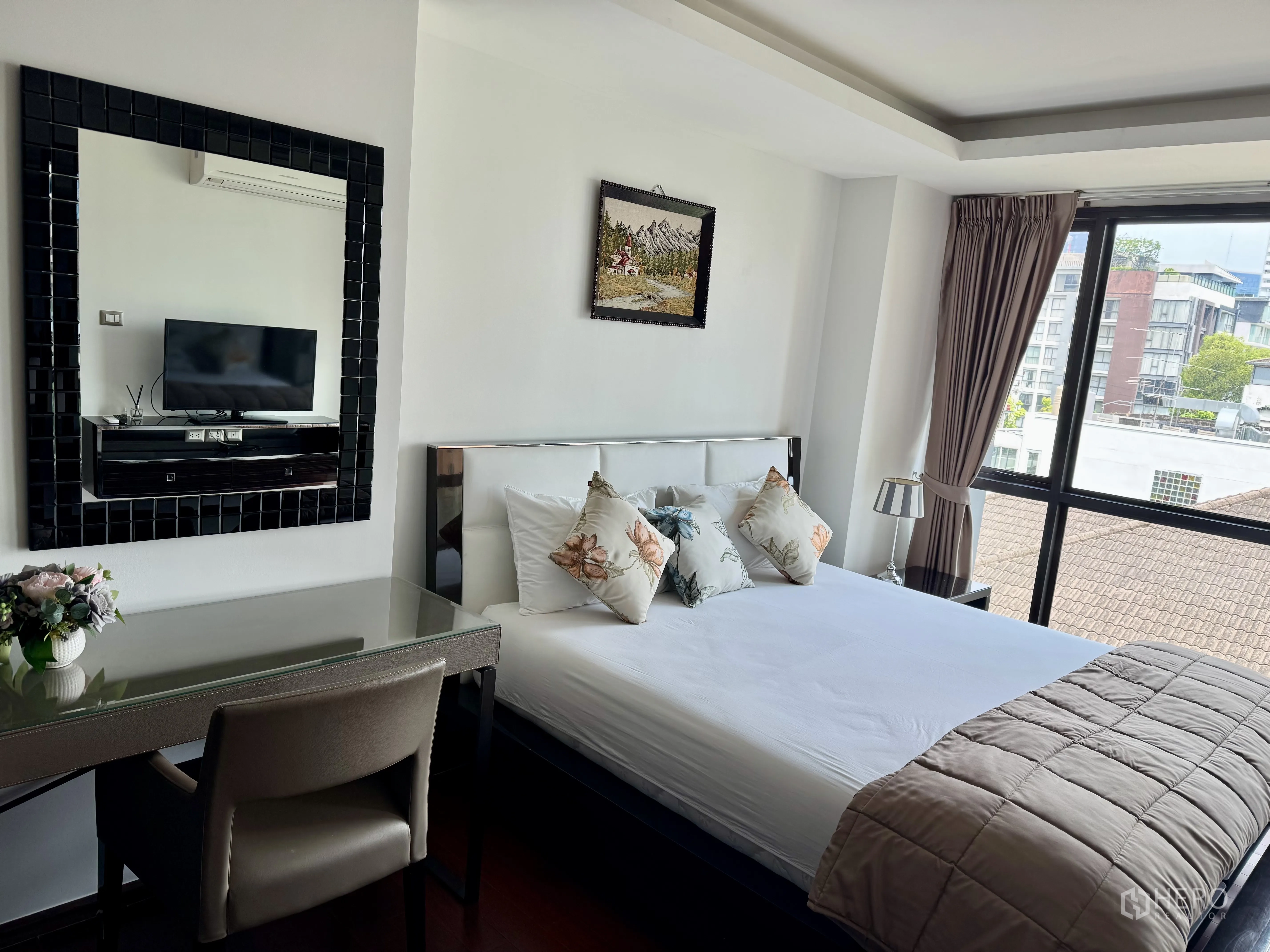 Condominium for rent in Watthana, Bangkok - Bright bedroom with large window, bed, desk, and wall mirror with TV console.