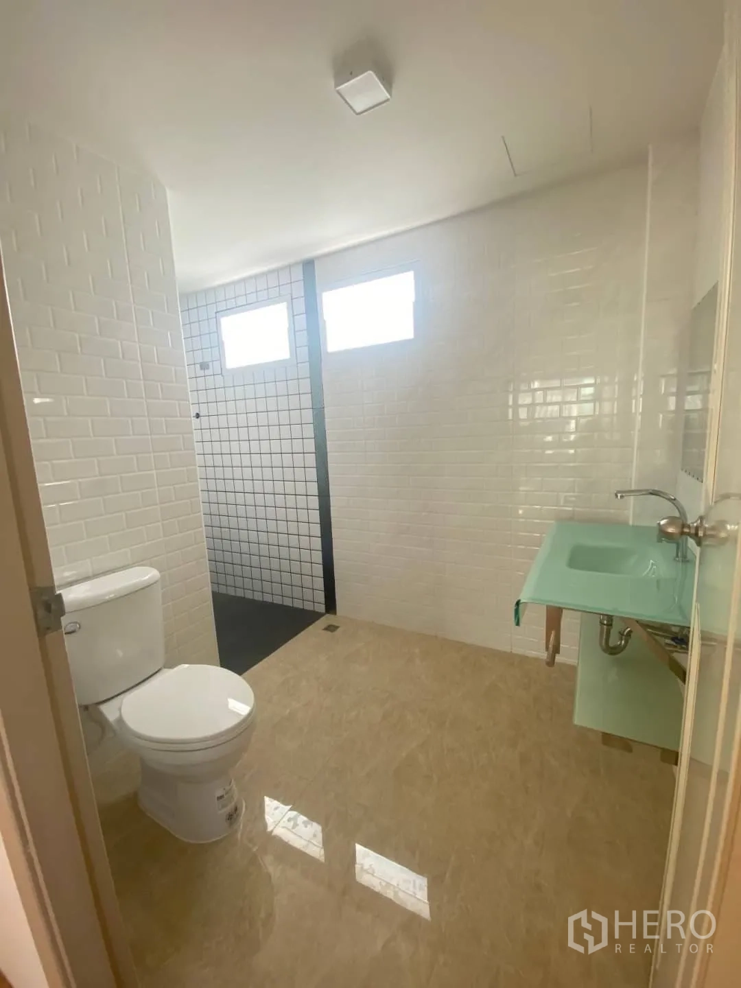 Home Office for sale - Modern bathroom with white subway tiles, glass vanity, toilet, and walk-in shower.