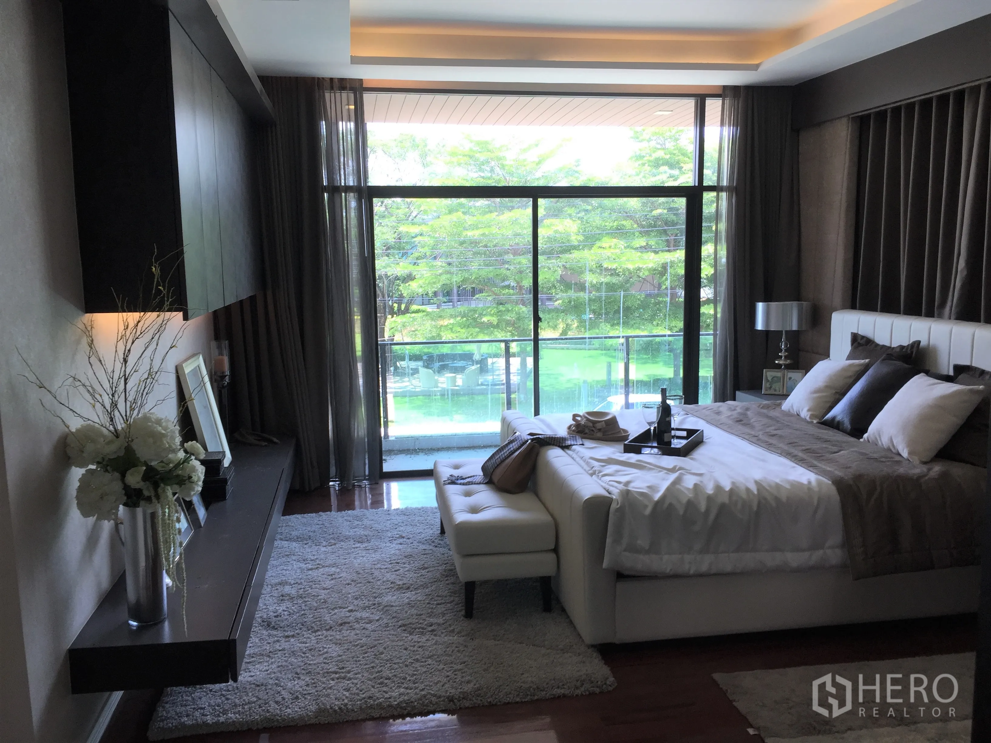 Detached House for sale in Prawet, Bangkok - Master suite with balcony and floor-to-ceiling glass overlooking greenery and pool.