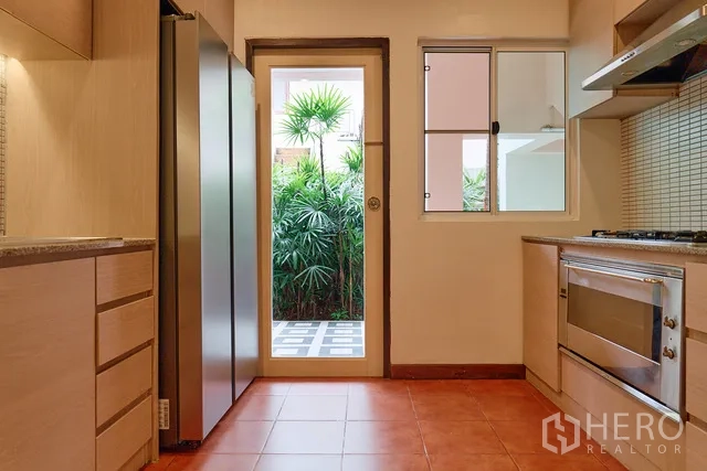 บ้าน ให้เช่าในWatthana, Bangkok - โถงครัวพร้อมตู้เย็นสูง ตู้เก็บของ และประตูออกสู่สวน