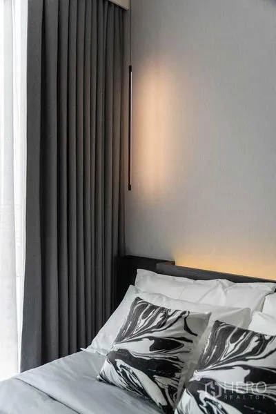 公寓 出租在Watthana, Bangkok - 卧室一角，层叠灰色窗帘、床头灯与花纹抱枕细节。