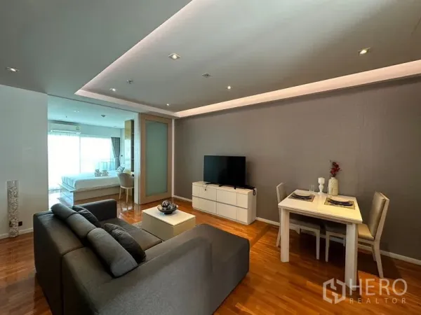 อพาร์ทเมนท์ ให้เช่าในKhlong Toei, Bangkok - ห้องนั่งเล่นและทานอาหารแบบโอเพ่นสเปซ โซฟาสีเทา ตู้วางทีวี และไฟฝ้าซ่อนไฟ