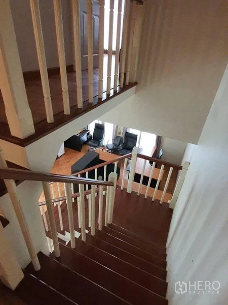 Townhouse for rent in Bueng Kum, Bangkok - Wood staircase with white balusters leading to upper levels and overlooking the living area.