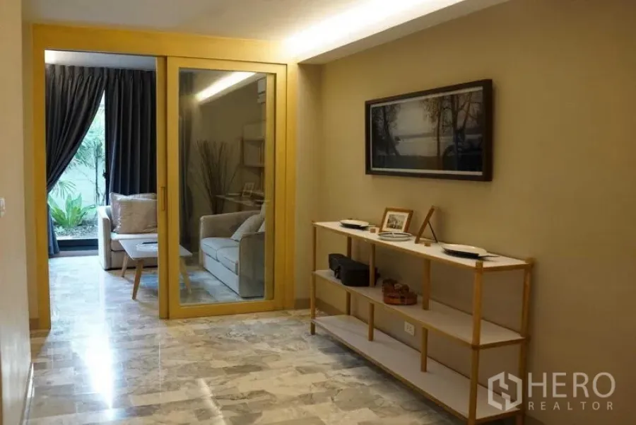 公寓 出租在Watthana, Bangkok - 入口走廊带展示架，玻璃门通向面向花园的休息室。