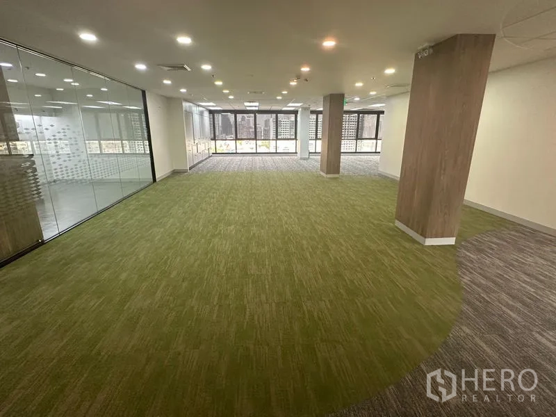 Office Space for rent in Khlong Toei, Bangkok - Collaboration zone with green carpet and glass walls overlooking city buildings.