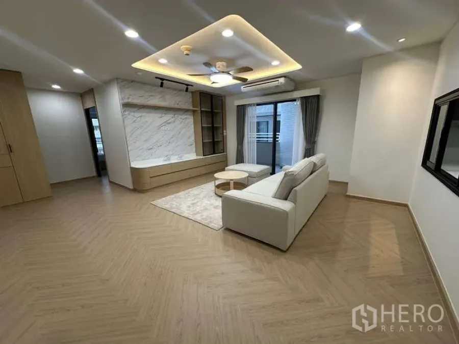 คอนโด ให้เช่าในWatthana, Bangkok - ห้องนั่งเล่นโซฟาเข้ามุม ผนังทีวีลายหินอ่อน และฝ้าซ่อนไฟ