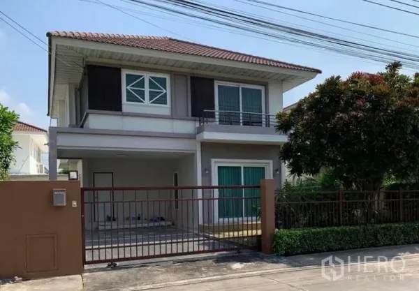 Detached House for sale in Bang Phli, Samut Prakan - Two-storey detached house exterior with gated parking, balcony, and landscaped front hedge.