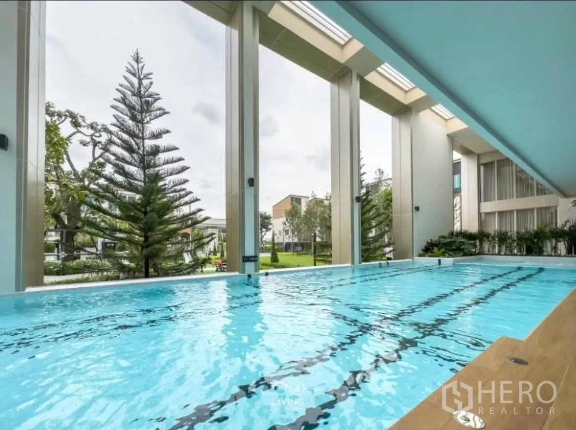 ทาวน์เฮาส์ for rent in Suan Luang, Bangkok - สระว่ายน้ำมีหลังคาพร้อมเลนว่ายและวิวสวนผ่านช่องเปิดสูง