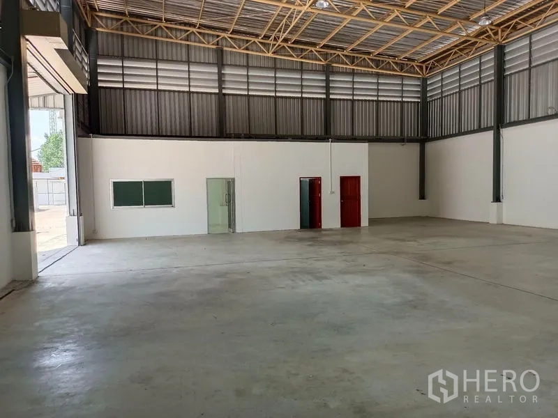 Warehouse for rent in Suan Luang, Bangkok - Wide open‑plan warehouse floor facing the office block and roller door.