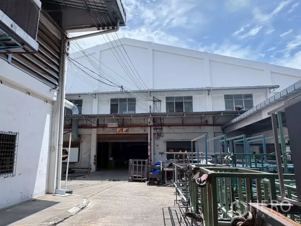 工厂 出租或出售在Bang Khun Thian, Bangkok - 两栋厂房之间的内院，设备推车、通风百叶与管线可见。