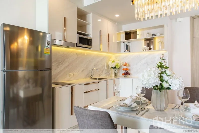 Condominium for rent in Pathum Wan, Bangkok - Kitchen and dining area with marble table set for four and a crystal chandelier.