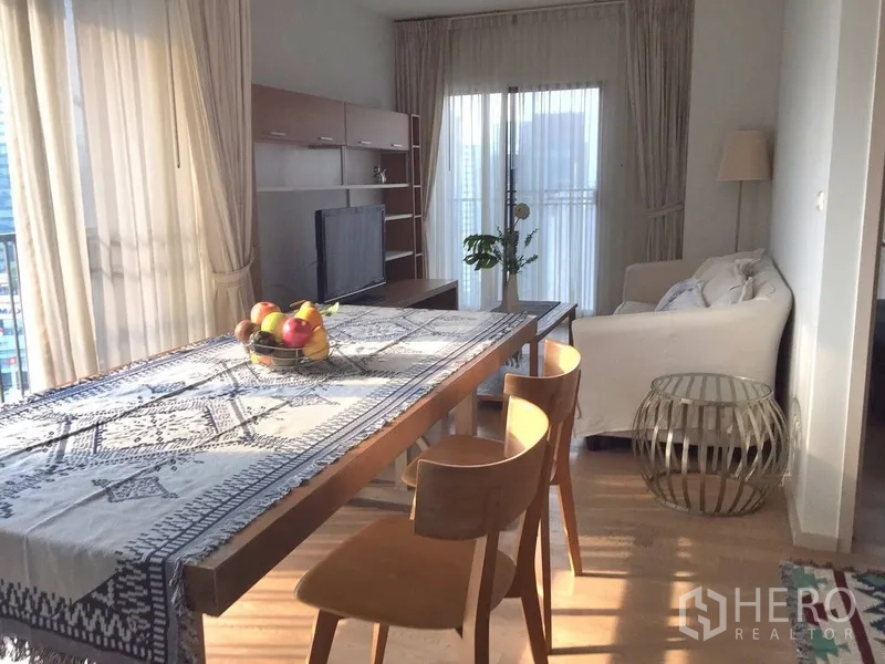 公寓 出租在Bangkok - 开放式餐区，长木桌与椅子，面向采光充足的客厅与阳台。