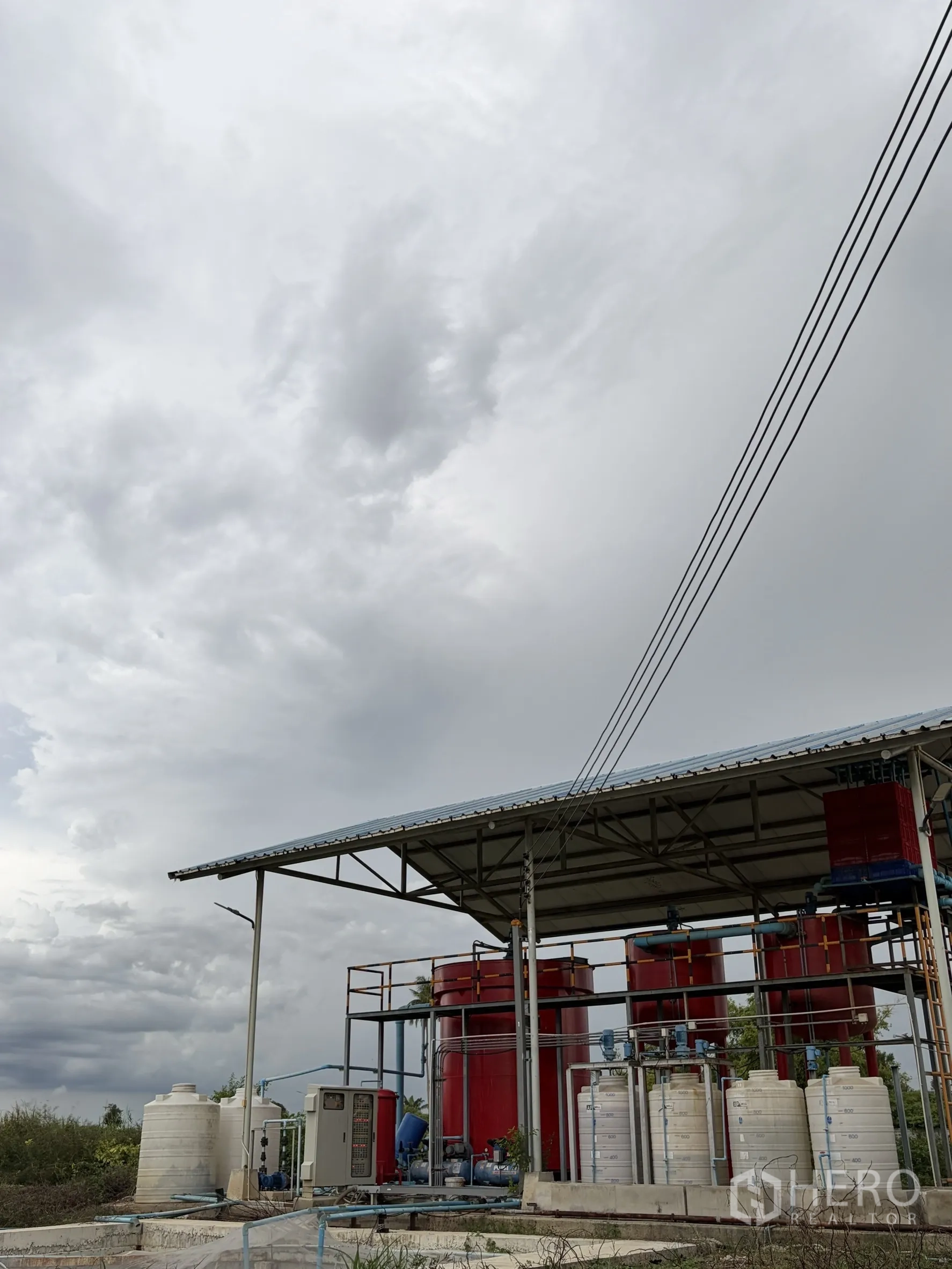 Factory for sale in Mueang Nakhon Pathom, Nakhon Pathom - Outdoor water treatment plant with red tanks and piping under a shelter.