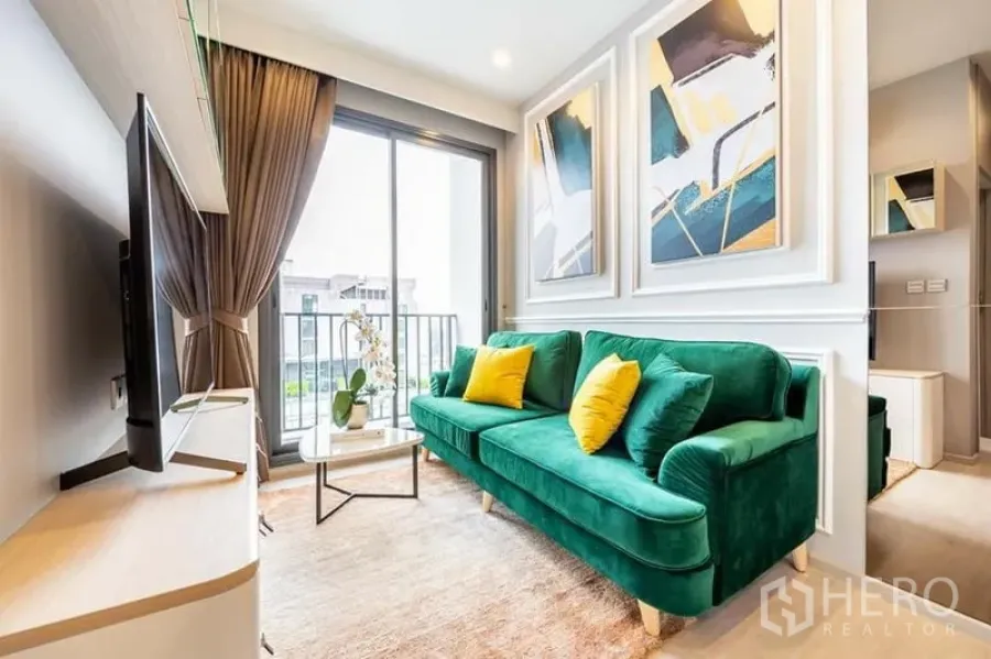 Condominium for rent or sale in Watthana, Bangkok - Compact lounge with green sofa, coffee table and sliding door to the balcony.