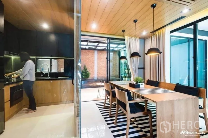 Townhouse for sale in Lak Si, Bangkok - Cozy terrace with wire-frame chair, side table, and potted plants.