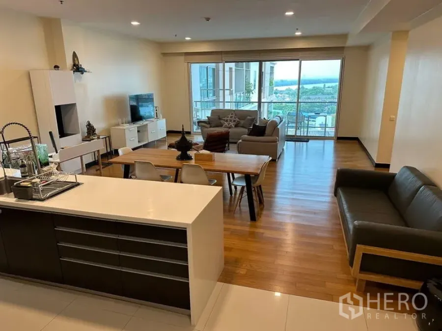 Condominium for rent in Yan Nawa, Bangkok - Open-plan lounge, dining, and kitchen with floor-to-ceiling windows to the balcony.