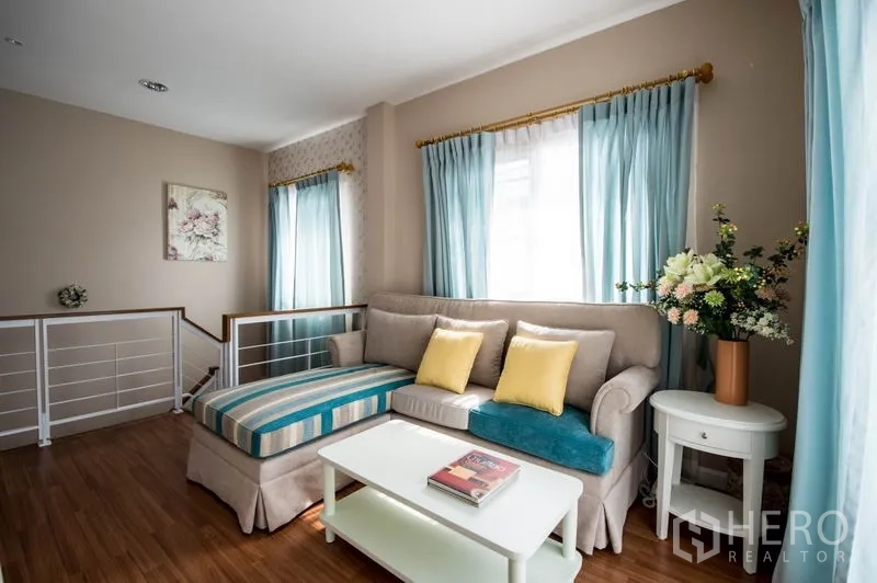 Detached House for sale in Bang Kapi, Bangkok - Open landing lounge with L-shaped daybed, coffee table and wood flooring.