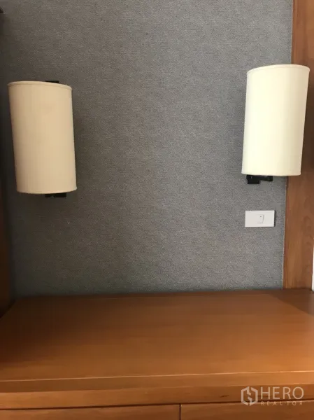 公寓 出租在Pathum Wan, Bangkok - 内置木质书桌或梳妆台，搭配成对壁灯与织物饰面。