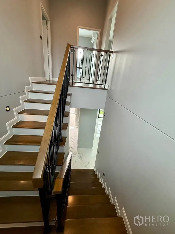 Detached House for rent in Don Mueang, Bangkok - Wood staircase with black metal balustrade connecting two floors.