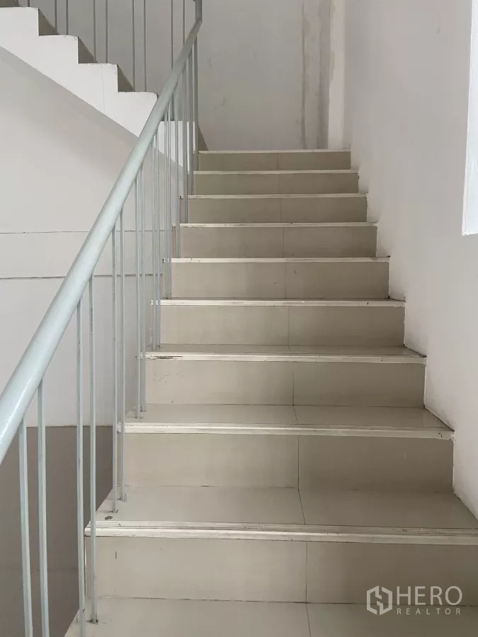 Shophouse for rent in Prawet, Bangkok - Internal tiled staircase with a metal handrail connecting multiple floors.