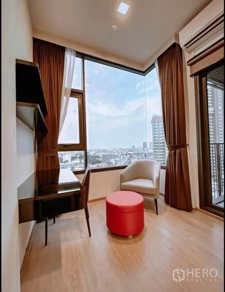 Condominium for sale in Chatuchak, Bangkok - Corner study area with desk, chair, ottoman and panoramic city views.