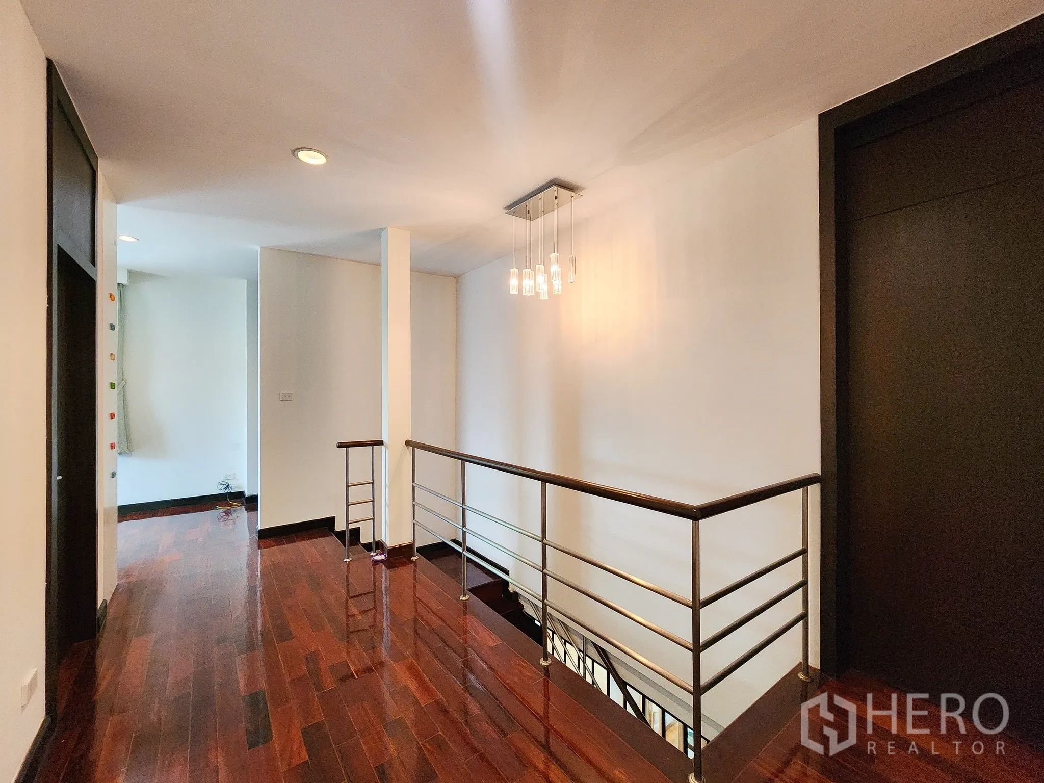 独立式住宅 出租在Bang Kapi, Bangkok - 二层走廊，吊灯与金属栏杆，实木地面。