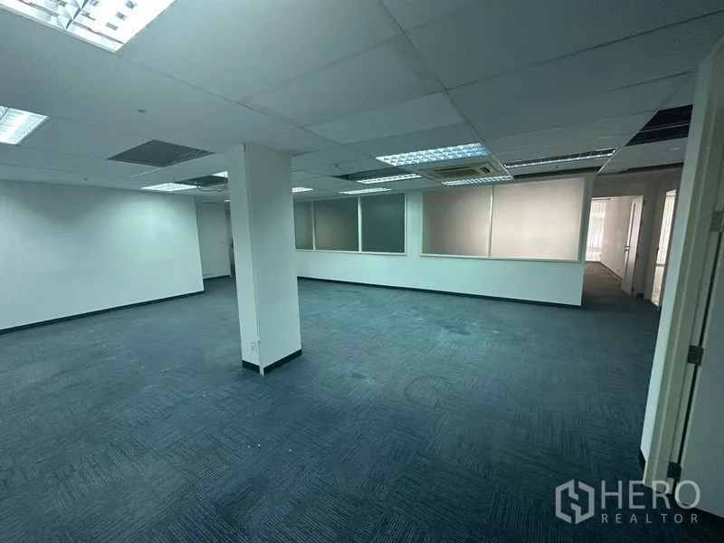 办公空间 出租在Khlong Toei, Bangkok - 宽敞的开放办公区，蓝色地毯、吊顶灯与磨砂内窗。