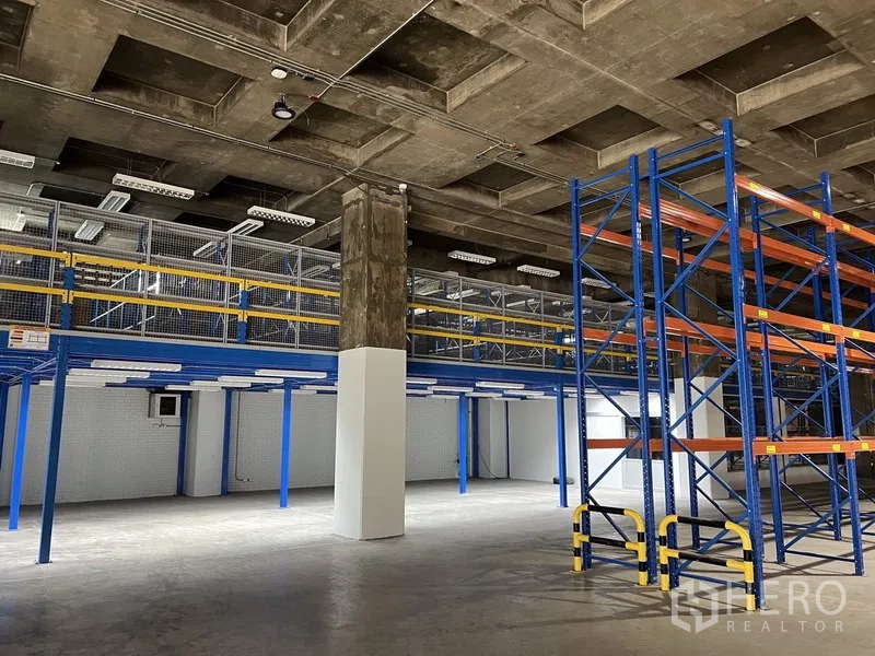Warehouse for rent in Chatuchak, Bangkok - Spacious warehouse interior in Chatuchak, Bangkok with mezzanine walkway, blue pallet racking, and a high coffered concrete ceiling.