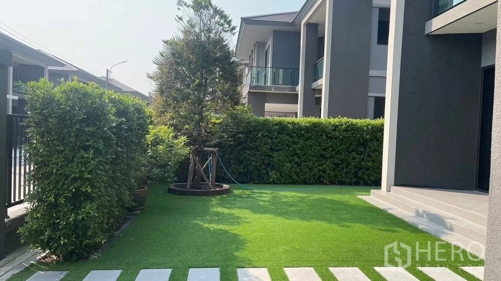 Detached House for rent in Prawet, Bangkok - Front yard with green lawn, hedges and neighboring modern houses.