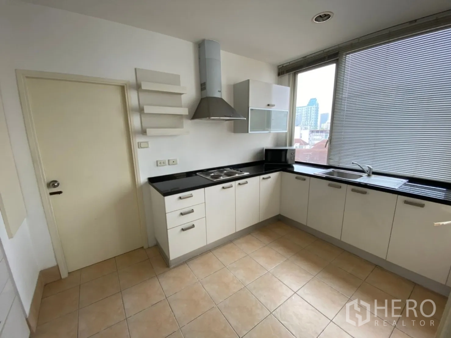 Condominium for rent in Watthana, Bangkok - U-shaped kitchen with white cabinetry, black countertops and a large window.