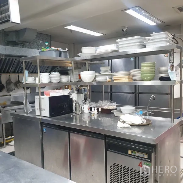 零售空间 出租在Khlong Toei, Bangkok - 后场备餐区，含不锈钢操作台、开放式餐具架与冷藏设备。