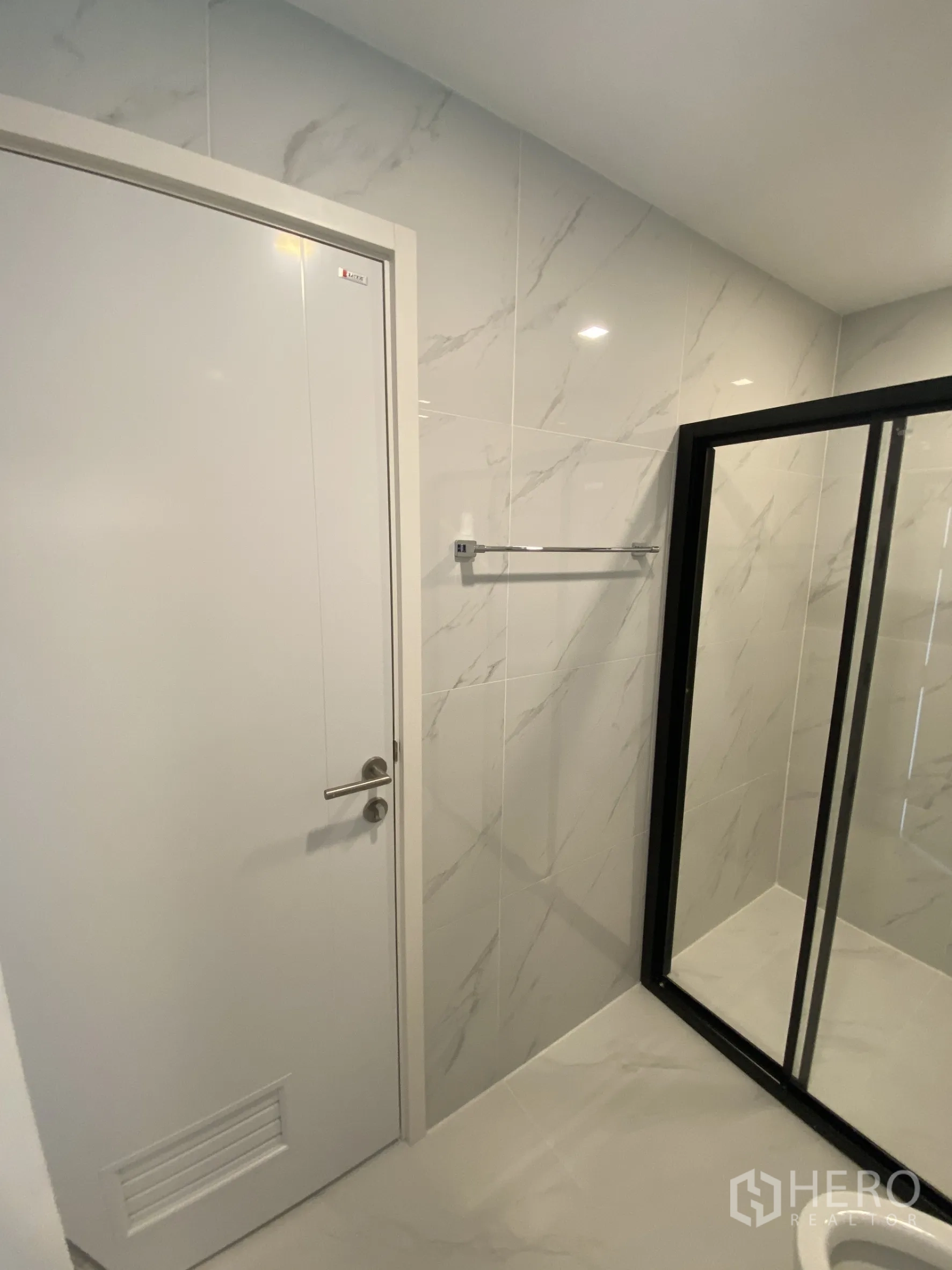 Townhouse for rent or sale in Bang Khae, Bangkok - Bathroom detail with shower enclosure and white door on marble-look tiles