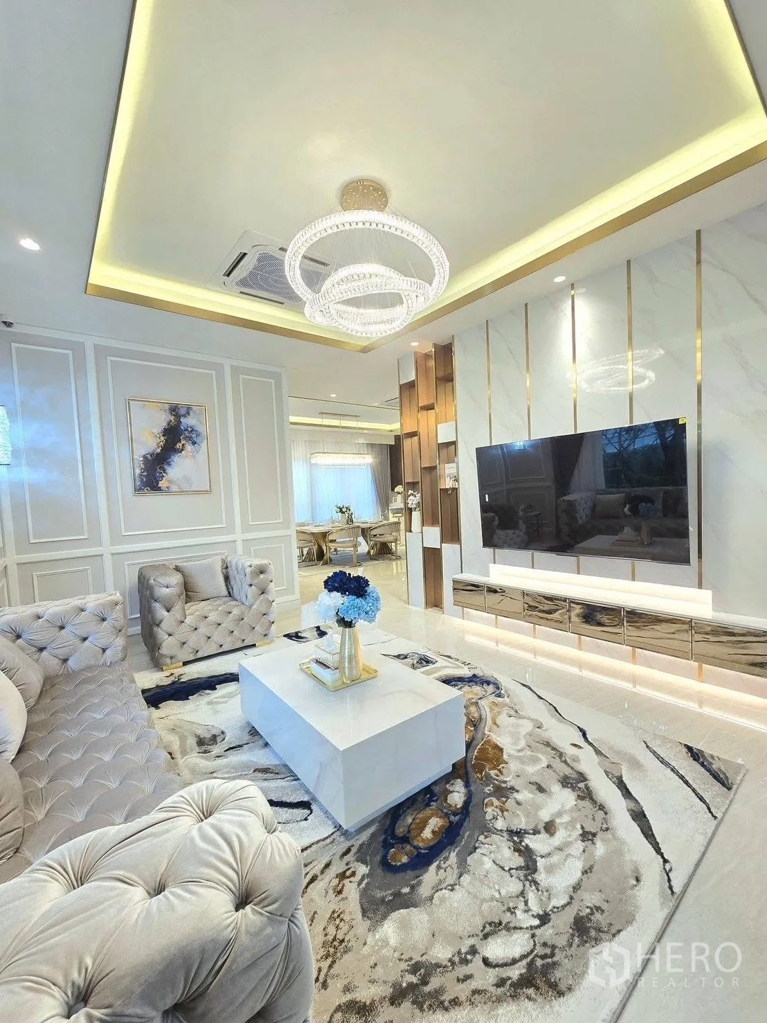 Detached House for rent or sale in Bang Phli, Samut Prakan - Living room toward dining area with marble TV console, patterned rug and decorative ceiling.