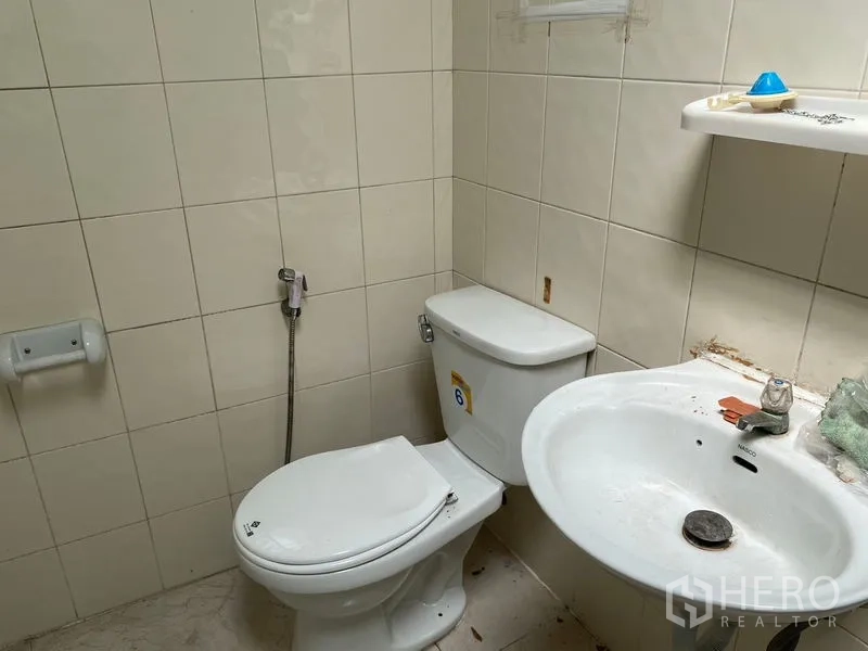 Warehouse for rent in Chatuchak, Bangkok - Toilet, sink, and spray hose in a tiled bathroom.