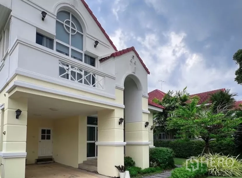 Detached House for rent or sale in Prawet, Bangkok - Close view of the arched entry and carport beside a landscaped garden.