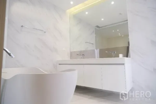 Home Office for rent or sale in Prawet, Bangkok - Bright marble-style bathroom with freestanding bathtub, long vanity and wide mirror.