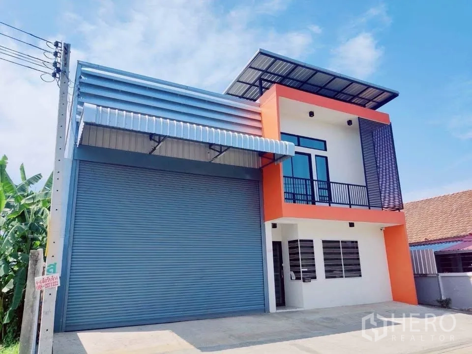 Warehouse for rent in Lam Luk Ka, Pathum Thani - New-build warehouse with oversized shutter and glass balcony under blue sky.