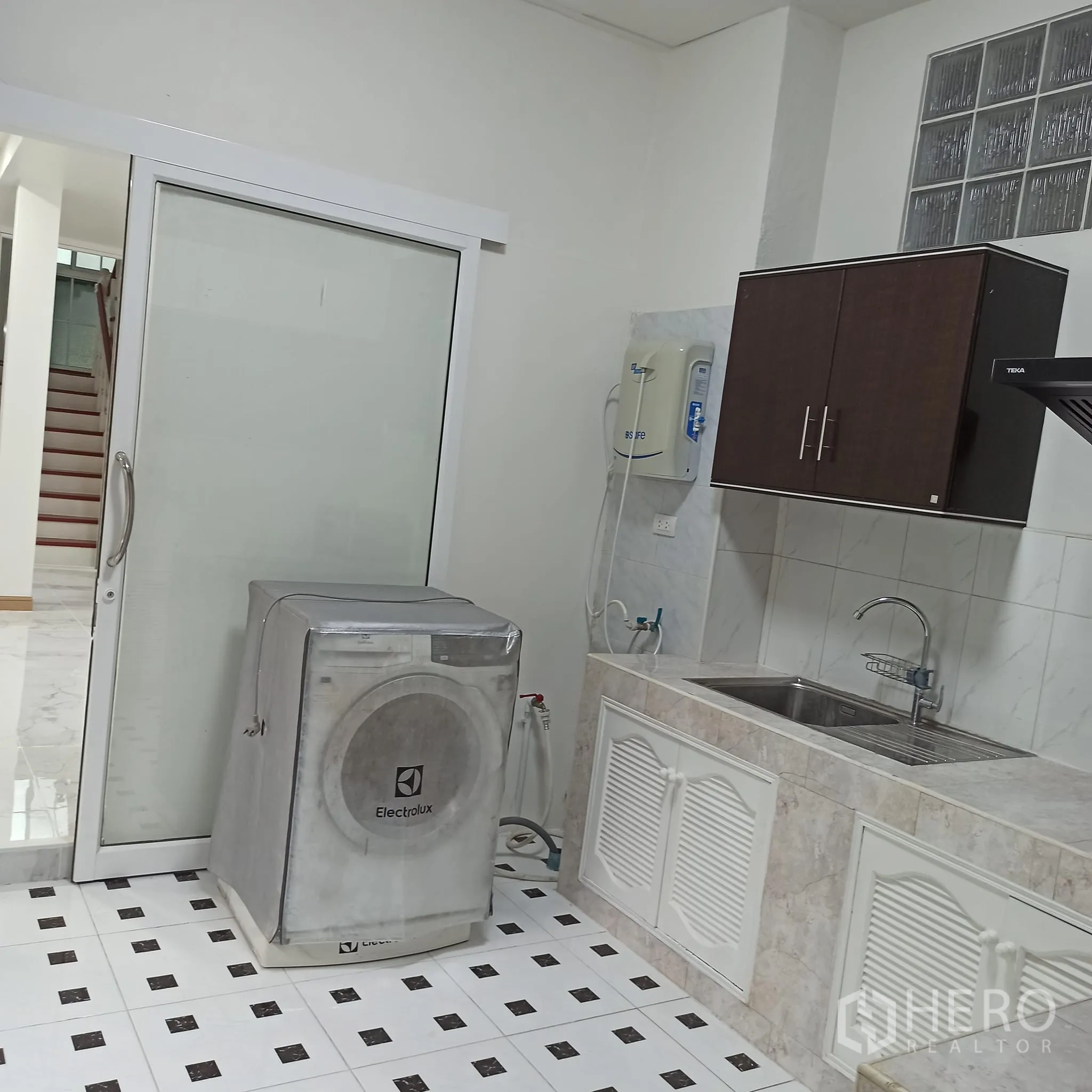 Townhouse for rent in Wang Thonglang, Bangkok - Kitchen with washing machine beside sliding door and sink.