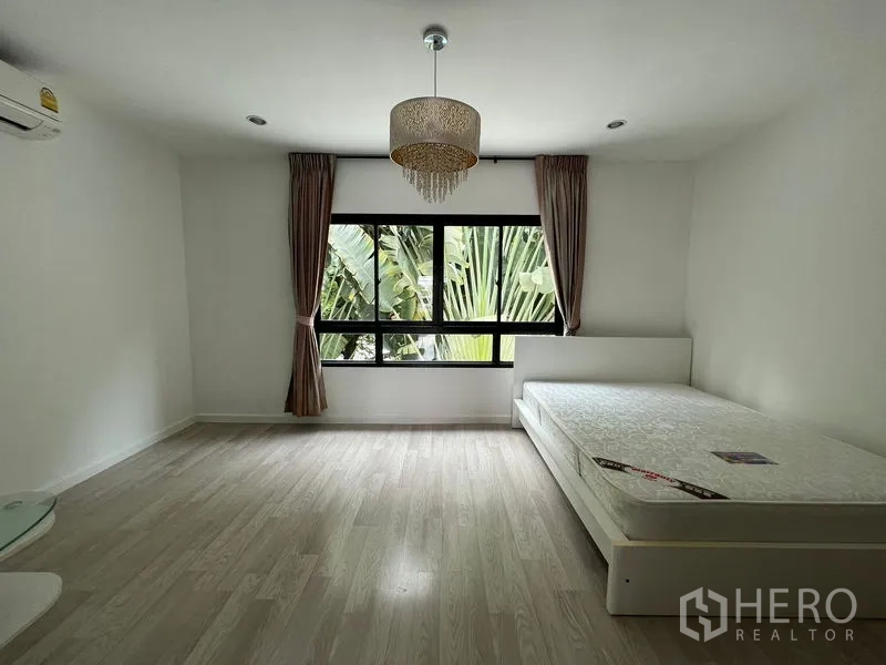 ทาวน์เฮาส์ ขายในBang Kapi, Bangkok - ห้องนอนพร้อมเตียงและโคมระย้า หน้าต่างใหญ่รับวิวสวน