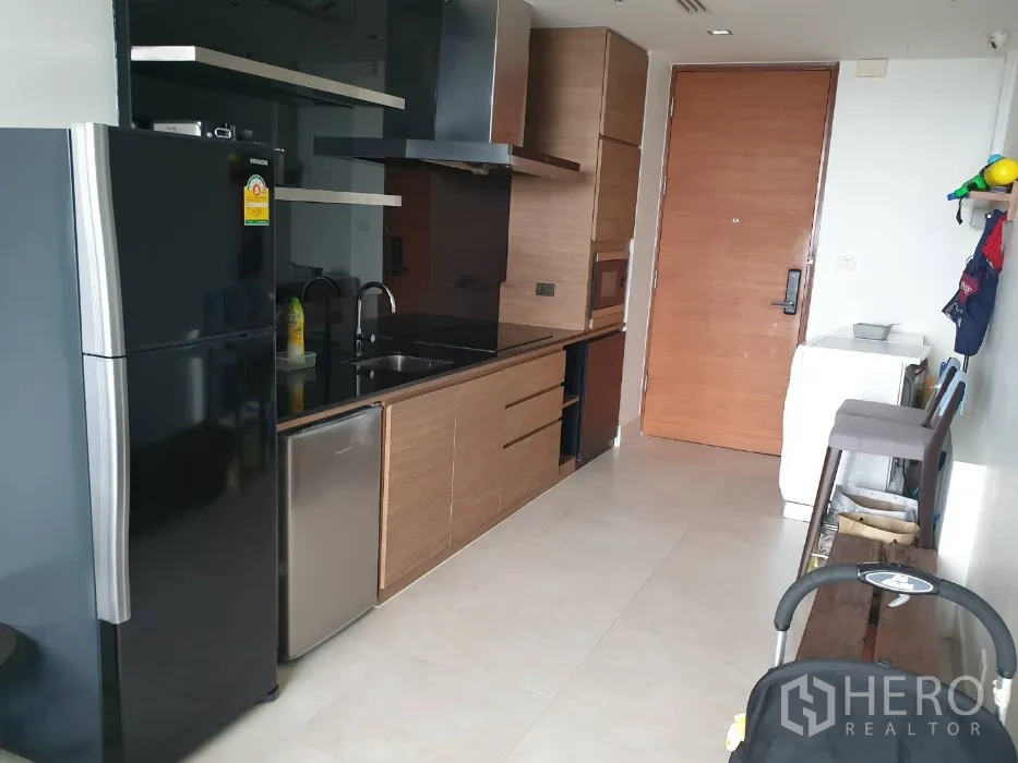 คอนโด ให้เช่าในKhlong Toei, Bangkok - ครัวบิวท์อินสมัยใหม่ มีตู้เย็นสีดำ ตู้ไม้ ซิงก์ และประตูทางเข้า