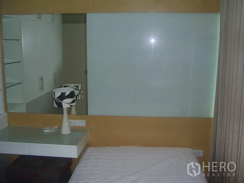 คอนโด ให้เช่าในKhlong Toei, Bangkok - มุมห้องนอนขนาดกะทัดรัด ผนังกระจกฝ้า โต๊ะทำงาน และผ้าม่าน