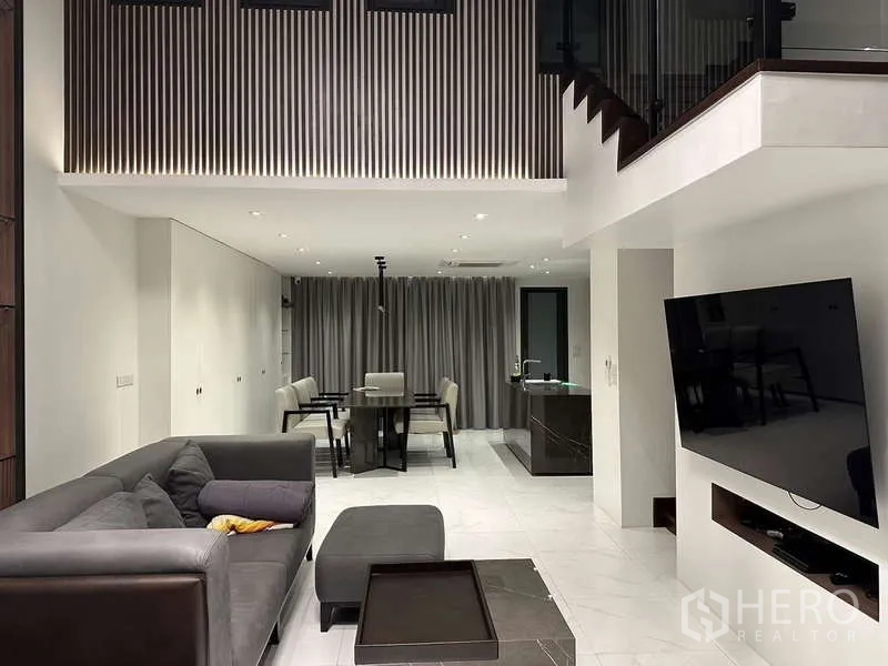 Townhouse for rent in Yan Nawa, Bangkok - Open-plan living and dining area with double-height ceiling and TV.