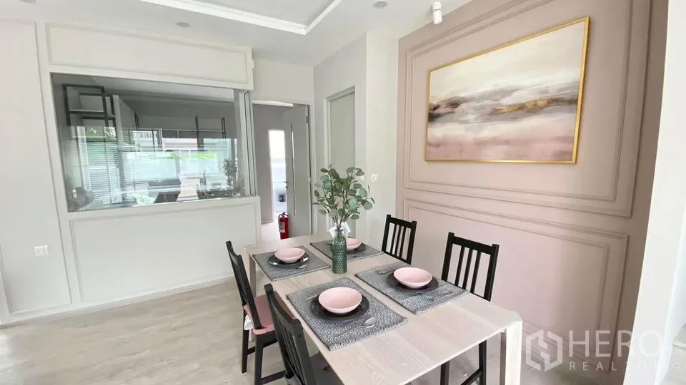 联排别墅 出租在Prawet, Bangkok - 四人餐区，特色装饰墙，透窗可见厨房。