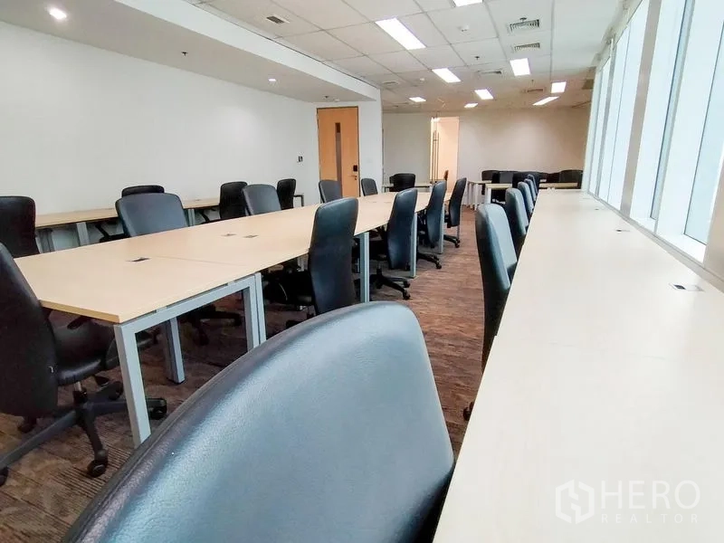Office Space for rent in Khlong Toei, Bangkok - Row of workstations beside full-height windows in a bright open-plan workspace.