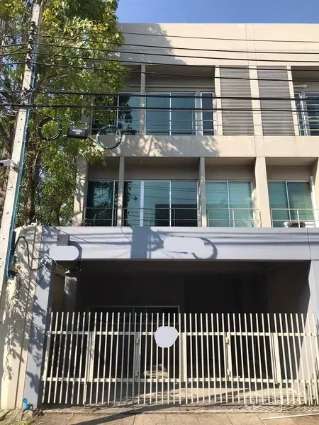 Townhouse for rent in Suan Luang, Bangkok - Modern three-storey townhouse facade with gated carport and large glass windows in Suan Luang.