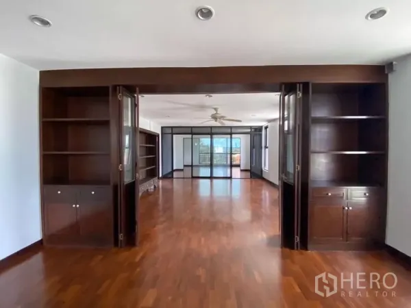 สำนักงานที่บ้าน ให้เช่าในPhra Khanong, Bangkok - ห้องกว้างพร้อมชั้นบิลท์อินไม้เข้ม ฉากกั้นกระจก พัดลมเพดาน และพื้นไม้เงางาม