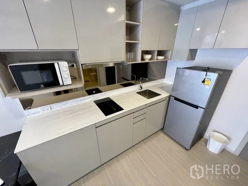 公寓 出租在Khlong Toei, Bangkok - 现代橱柜一字型厨房，配电磁炉、微波炉和不锈钢冰箱。
