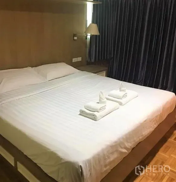 คอนโด ให้เช่าในSathon, Bangkok - ห้องนอนอบอุ่น เตียงคิงไซส์ ชุดผ้าปูสีขาว ผ้าเช็ดตัวพับ และผ้าม่านกันแสงสีเข้ม