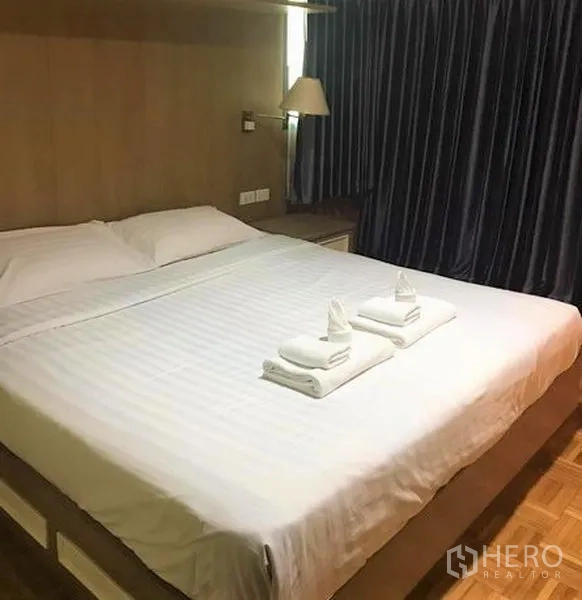 คอนโด ให้เช่าในSathon, Bangkok - ห้องนอนอบอุ่น เตียงคิงไซส์ ชุดผ้าปูสีขาว ผ้าเช็ดตัวพับ และผ้าม่านกันแสงสีเข้ม