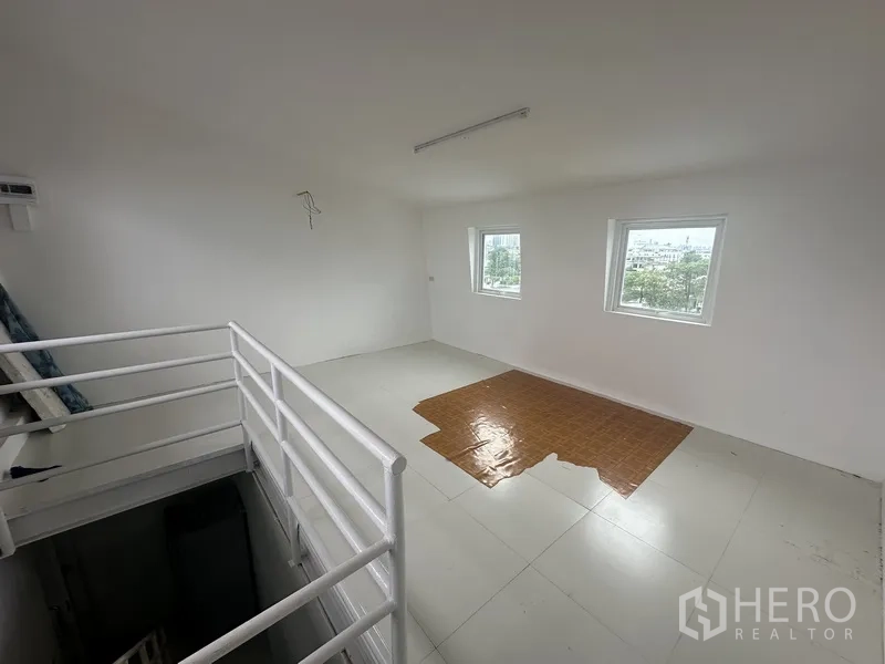 Office Space for rent or sale - Compact mezzanine office with stair railing and two square windows.